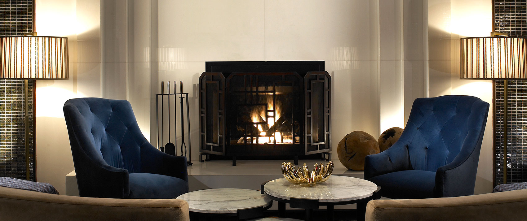 Kimpton Hotel Palomar Philadelphia lobby living room with seating, circular marbletop coffee tables, and a fireplace